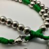 Rosenkranz mit 6mm Metallperlen und grüner Kordel liegt auf weisen Hintergrund - Nahaufnahme einiger Perlen und dem Kettenverschluss