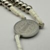 Rosenkranz mit 6mm Metallperlen und weisser Kordel liegt auf weissen Hintergrund - Nahaufnahme der Benediktusmedaille Vorderseite mit dem hl. Benedikt