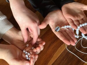 Kinder basteln gemeinsam einen Rosenkranz