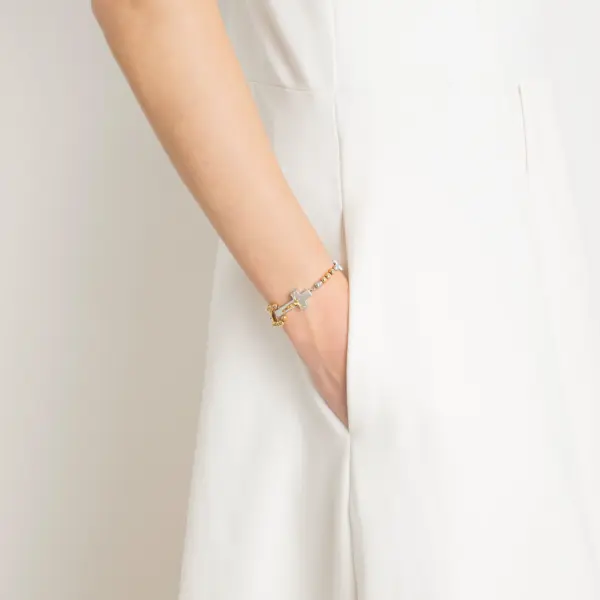 Eine Frau trägt ein Rosenkranz-Armband von Ghirelli - Rosalet mit traditionellen Kreuz in Gold und Silber.