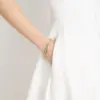 Eine Frau trägt das Rosenkranz-Armband Rosalet mit Goldperlen und Kristallbesatz.