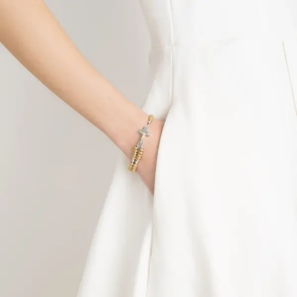 Eine Frau trägt das Rosenkranz-Armband Rosalet mit Goldperlen und Kristallbesatz.