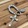 Rosenkranz Schlüsselanhänger mit Benediktuskreuz und verzierter wundertätigen Medaille. Die Perlen sind weise Perlen mit silbernen Kreuzsymbolen.