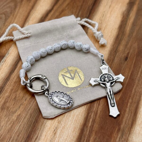 Rosenkranz Schlüsselanhänger mit weißen Perlen und Kreuzmotiv auf einem Baumwollbeutel