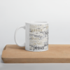 Weiße Tasse mit dem Namen Jesus in allen Sprachen der Welt auf einem Holzbrett - Henkel nach links.