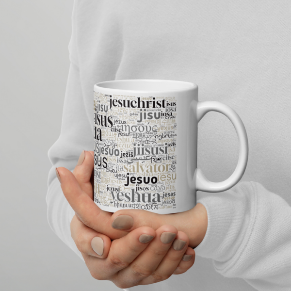 Man sieht Frauenhände, die eine weiße Tasse mit der Aufschrift "Jesus" in verschiedenen Sprachen hält.