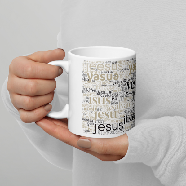Zwei Frauenhände halten eine weiße Tasse mit dem Namen Jesus in verschiedenen Sprachen - die rechte Hand hält den Henkel.