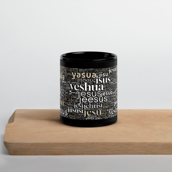 Schwarze Tasse mit dem Namen Jesus in allen Sprachen der Welt auf einem Holzbrett in Frontansicht
