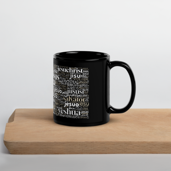 Schwarze Tasse mit dem Namen Jesus in allen Sprachen der Welt auf einem Holzbrett mit dem Henkel nach rechts