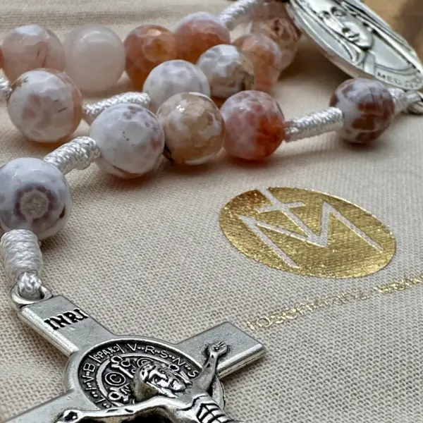 Benediktuskreuz des Feuerachat-Rosenkranzes im Detail auf dem Geschenkbeutel