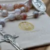 Benediktuskreuz des Rosenkranz Medjugorje Feuerachat auf dem Geschenkbeutel