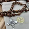 Benediktus-Sternkreuz des Walnussholz-Rosenkranzes auf dem Geschenkbeutel