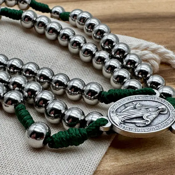 Wundertätige Medaille zwischen Edelstahlperlen auf grüner Kordel, auf dem Geschenkbeutel