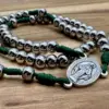 Wundertätige Medaille und Edelstahlperlen mit grüner Kordel in Nahaufnahme