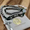 Rosenkranz aus Edelstahl mit grüner Kordel und Benediktuskreuz auf dem Geschenkbeutel