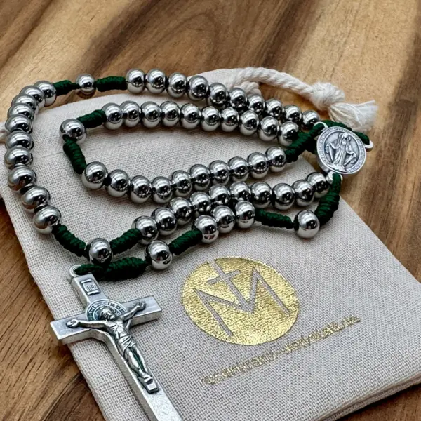 Rosenkranz aus Edelstahl mit grüner Kordel und Benediktuskreuz auf dem Geschenkbeutel