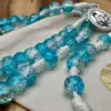 Türkis-klare Crackle-Glasperlen des Schönstatt Rosenkranzes auf dem Geschenkbeutel